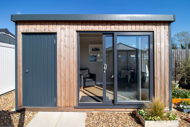 Summerhouse with grey doors and vertical timber cladding