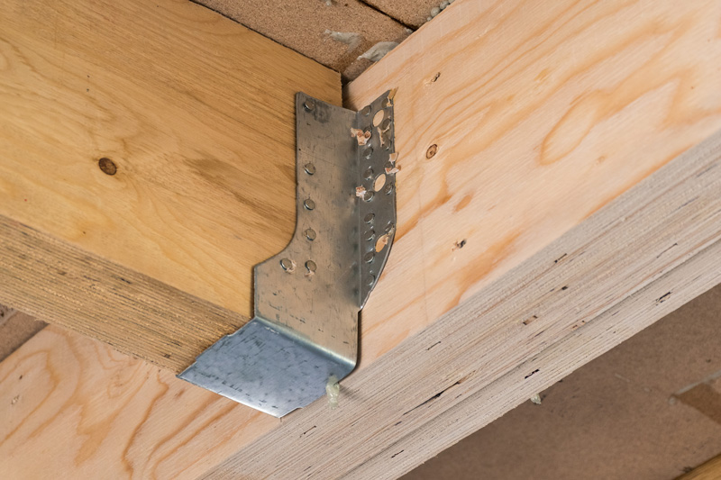 a wooden joist fixed to a beam with a timber to timber joist hanger