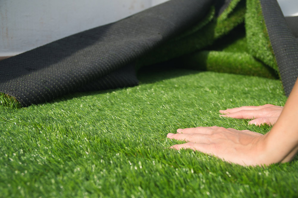 A person laying artificial grass.
